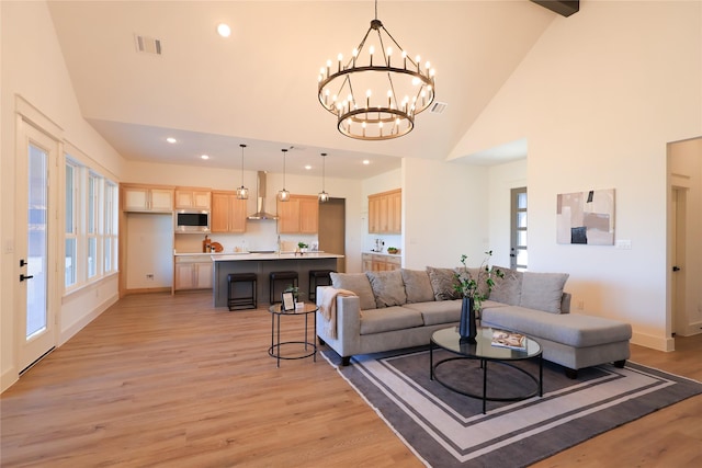 living area featuring high vaulted ceiling, light wood-style flooring, visible vents, recessed lighting, and a chandelier