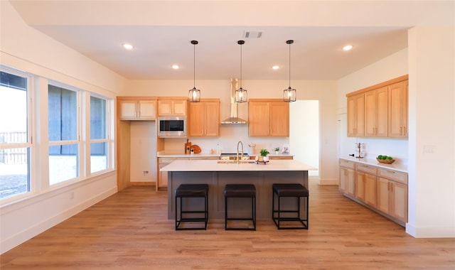 kitchen with stainless steel microwave, light brown cabinets, light countertops, visible vents, and a sink