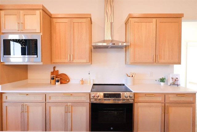 kitchen featuring wall chimney range hood, appliances with stainless steel finishes, and light brown cabinetry