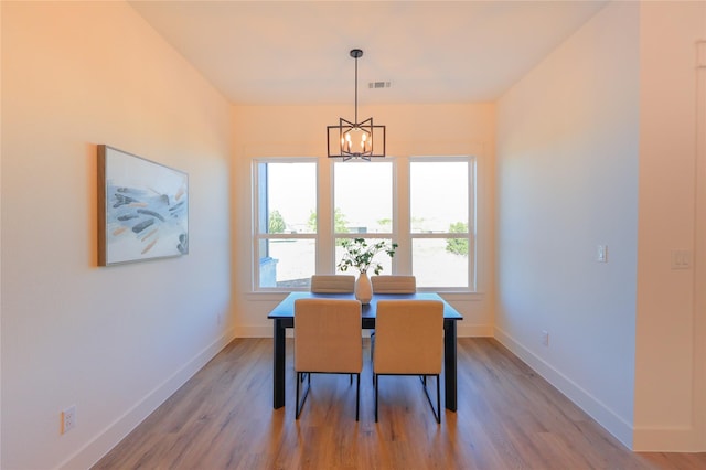 dining space with a wealth of natural light, visible vents, an inviting chandelier, and light wood-style flooring