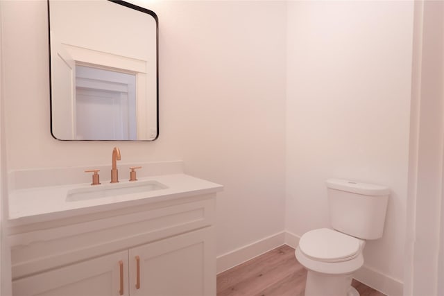bathroom featuring toilet, vanity, wood finished floors, and baseboards