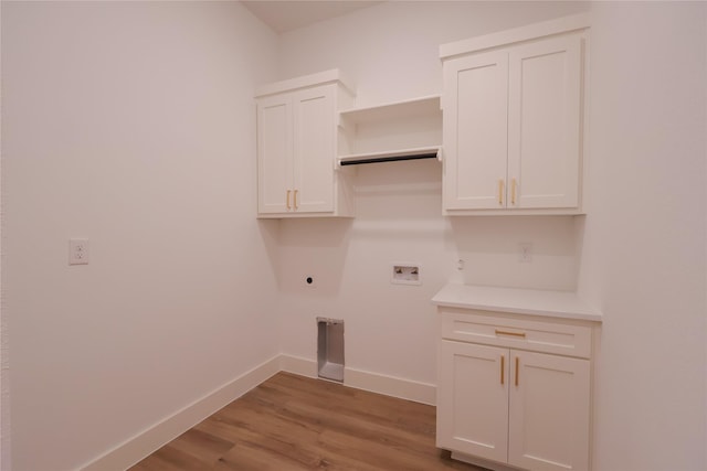 washroom with hookup for an electric dryer, baseboards, light wood-style flooring, hookup for a washing machine, and cabinet space