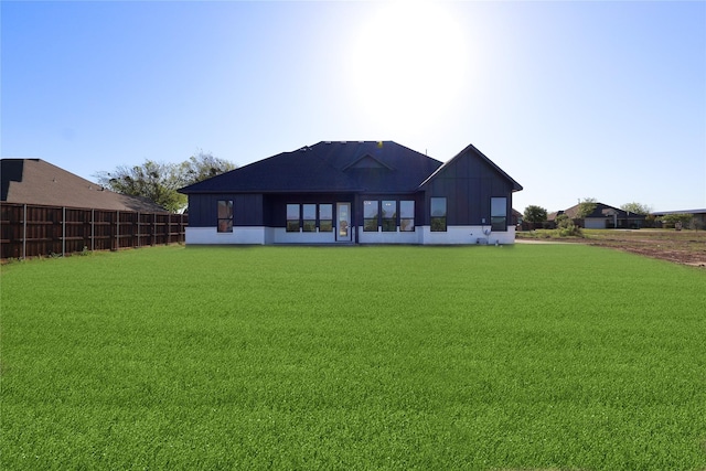 back of property featuring fence and a lawn