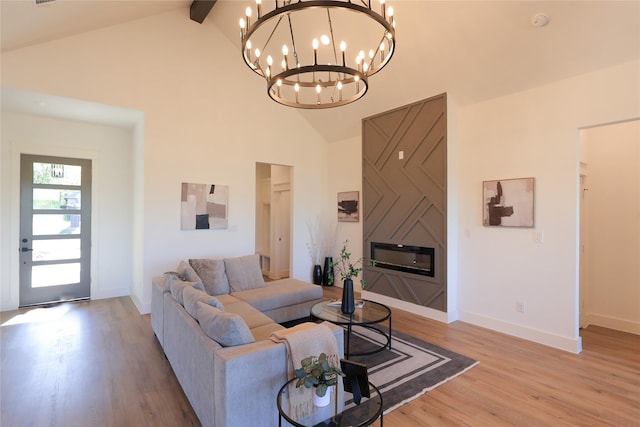 living room featuring a large fireplace, baseboards, a chandelier, light wood-style flooring, and high vaulted ceiling