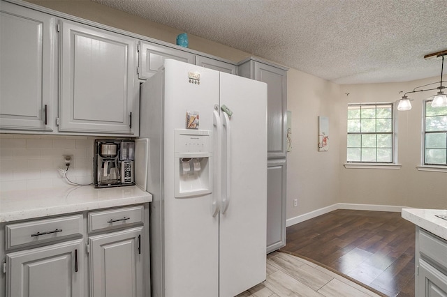 603 S 2nd St, Midlothian, TX 76065 - kitchen with white refrigerator with ice dispenser, a textured ceiling, tasteful backsplash, baseboards, and decorative light fixtures