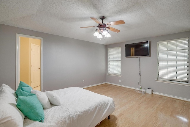 603 S 2nd St, Midlothian, TX 76065 - bedroom with light wood finished floors, baseboards, a textured ceiling, and a ceiling fan