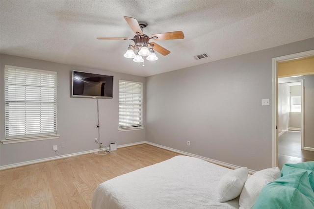 603 S 2nd St, Midlothian, TX 76065 - bedroom with light wood finished floors, baseboards, a textured ceiling, and ceiling fan