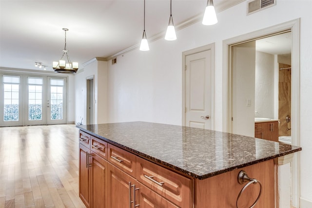 3818 Holland Ave Unit 305, Dallas, TX 75219 - kitchen featuring crown molding, visible vents, decorative light fixtures, brown cabinets, and a notable chandelier