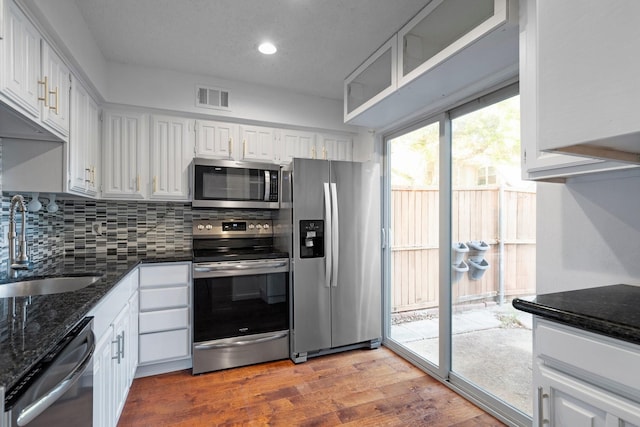 851 Dublin Dr Unit 3, Richardson, TX 75080 - kitchen featuring appliances with stainless steel finishes, a sink, white cabinetry, dark stone counters, and wood finished floors