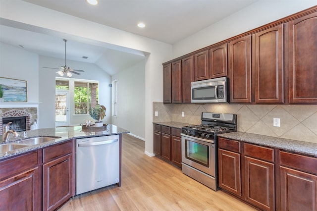 5208 Birchwood Dr, Mckinney, TX 75071 - kitchen featuring a ceiling fan, dark stone counters, lofted ceiling, light wood finished floors, and appliances with stainless steel finishes