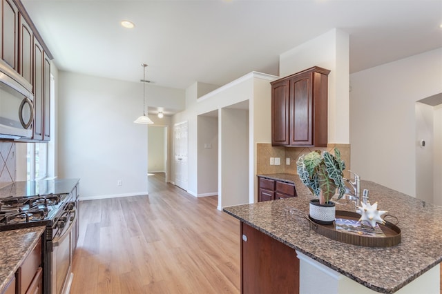 5208 Birchwood Dr, Mckinney, TX 75071 - kitchen featuring dark stone countertops, light wood-type flooring, decorative backsplash, and stainless steel appliances