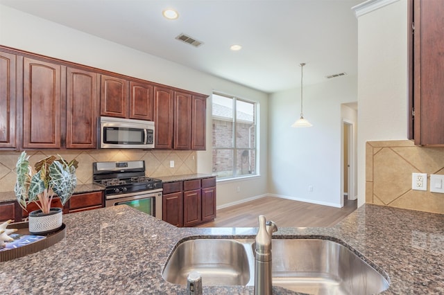 5208 Birchwood Dr, Mckinney, TX 75071 - kitchen featuring dark stone counters, appliances with stainless steel finishes, a sink, and visible vents