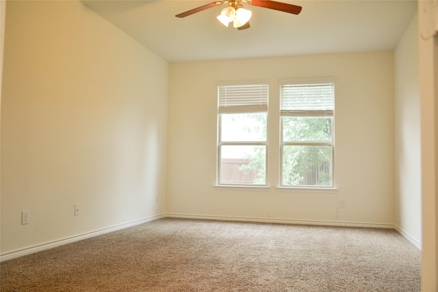 carpeted spare room featuring a ceiling fan and baseboards