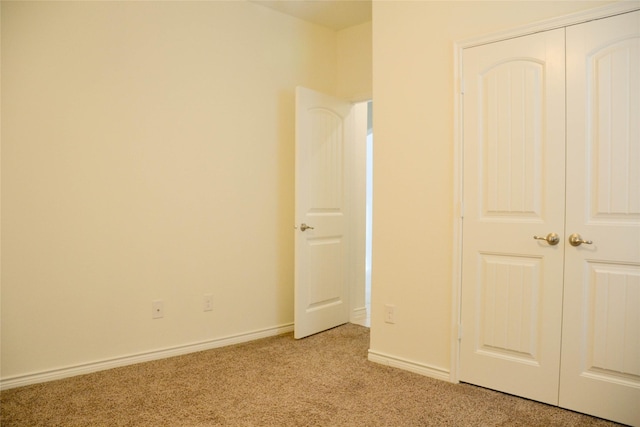 unfurnished bedroom with light colored carpet, a closet, and baseboards