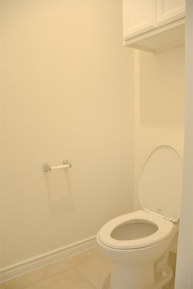 bathroom with tile patterned flooring, baseboards, and toilet