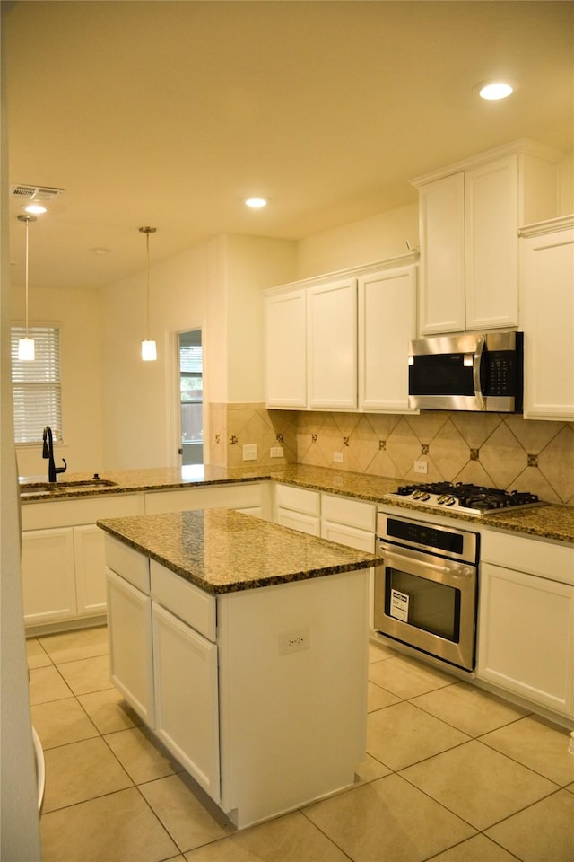 kitchen featuring appliances with stainless steel finishes, a sink, decorative backsplash, white cabinetry, and recessed lighting