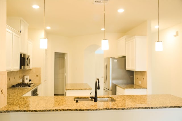 kitchen featuring a sink, stainless steel appliances, decorative backsplash, light stone countertops, and arched walkways