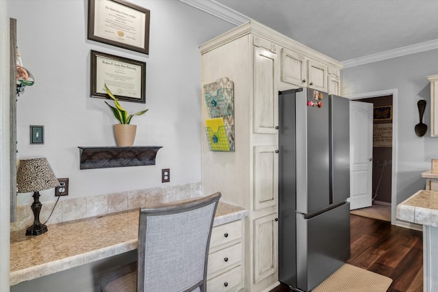 kitchen featuring dark wood-style flooring, cream cabinets, light countertops, freestanding refrigerator, and ornamental molding