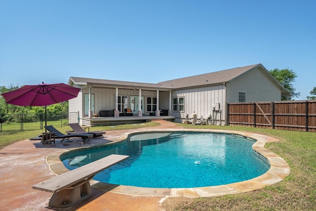 view of swimming pool featuring a deck, a fenced backyard, a fenced in pool, a patio area, and a lawn
