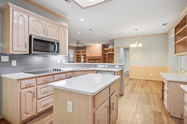 kitchen with appliances with stainless steel finishes, a sink, a peninsula, ceiling fan, and light countertops