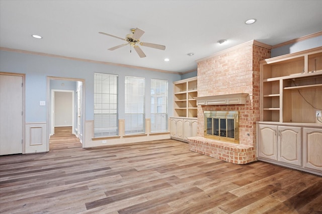 unfurnished living room featuring crown molding, a ceiling fan, light wood-type flooring, a fireplace, and recessed lighting