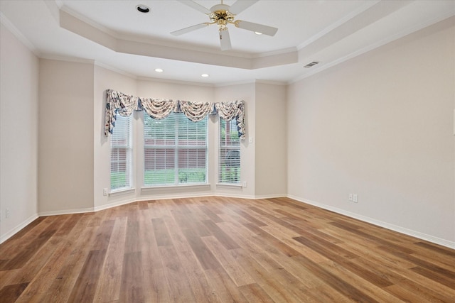 unfurnished room with a raised ceiling, wood finished floors, crown molding, baseboards, and recessed lighting