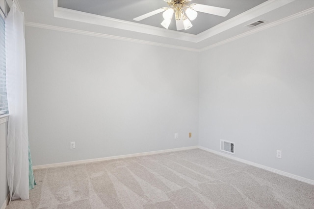 carpeted spare room featuring a tray ceiling, ceiling fan, ornamental molding, and baseboards