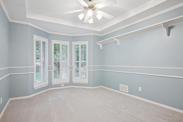 carpeted empty room featuring a ceiling fan, a tray ceiling, baseboards, and ornamental molding