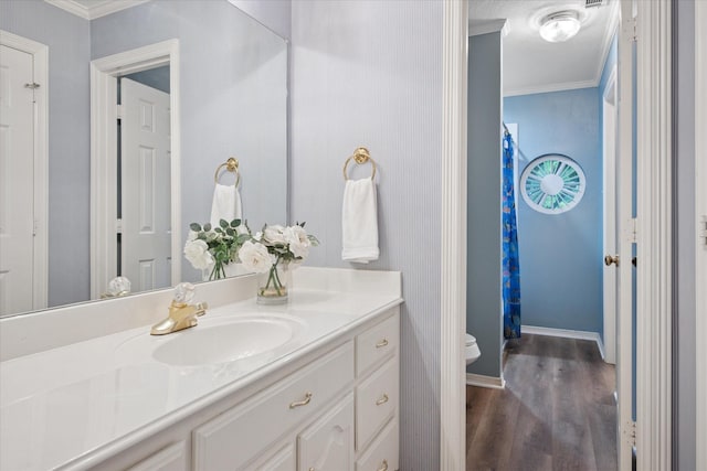 bathroom featuring crown molding, toilet, wood finished floors, vanity, and baseboards
