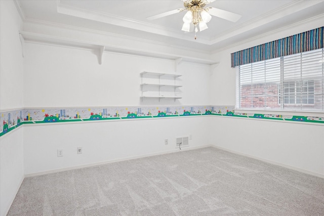 carpeted spare room featuring ornamental molding, a raised ceiling, a ceiling fan, and baseboards