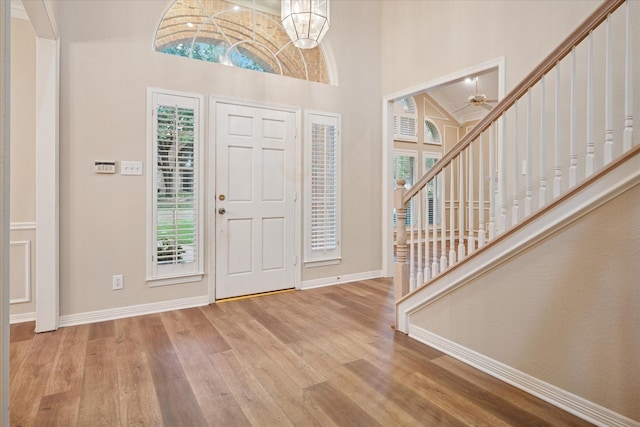 foyer with healthy amount of natural light, baseboards, a high ceiling, and wood finished floors