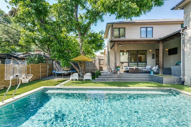rear view of property featuring a fenced in pool, a fenced backyard, a trampoline, and outdoor lounge area