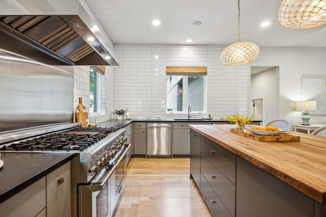6604 Northridge Dr, Dallas, TX 75214 - kitchen with stainless steel appliances, wood counters, wall chimney range hood, a sink, and decorative backsplash
