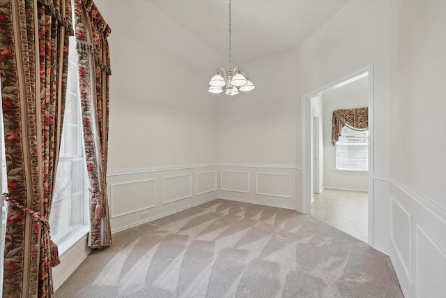 unfurnished dining area with a chandelier, a decorative wall, carpet, and a wainscoted wall