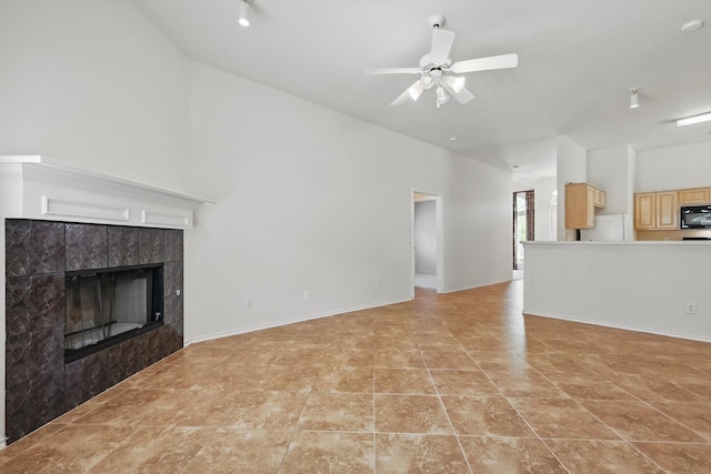 unfurnished living room featuring a tile fireplace, a ceiling fan, light tile patterned flooring, and high vaulted ceiling
