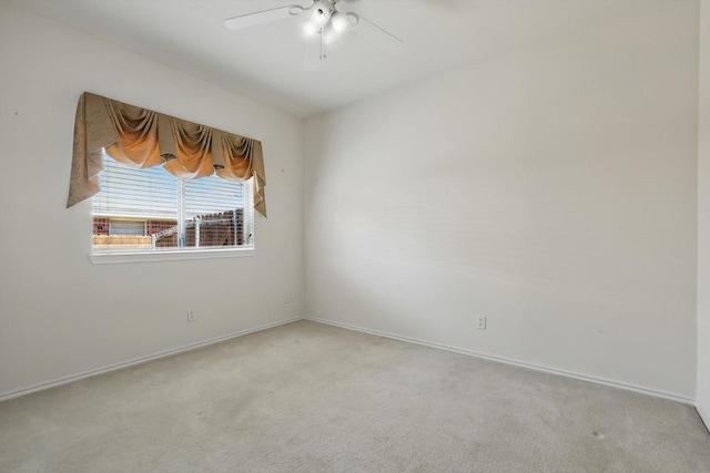 carpeted empty room featuring a ceiling fan and baseboards