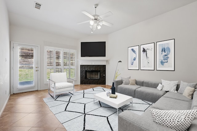 living room featuring baseboards, a ceiling fan, a fireplace, and light tile patterned floors