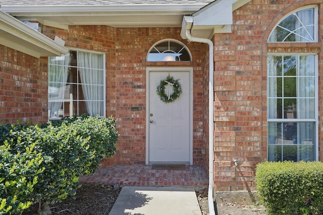 entrance to property with brick siding and roof with shingles