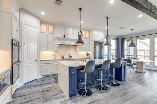 8321 Burnley, The Colony, TX 75056 - kitchen with light wood-style flooring, decorative backsplash, a sink, white cabinets, and light countertops