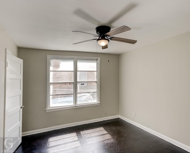 spare room with dark wood-type flooring, baseboards, and a ceiling fan
