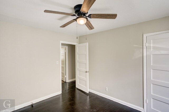 empty room with dark wood-style floors, baseboards, and a ceiling fan
