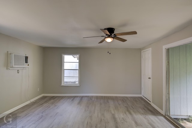 empty room with wood finished floors, ceiling fan, baseboards, and a wall unit AC