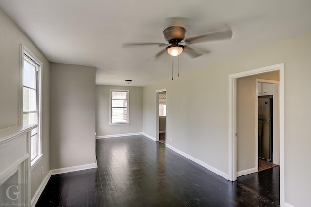 empty room with dark wood-style flooring, baseboards, and ceiling fan