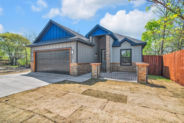 view of front facade with concrete driveway, board and batten siding, stone siding, a garage, and fence