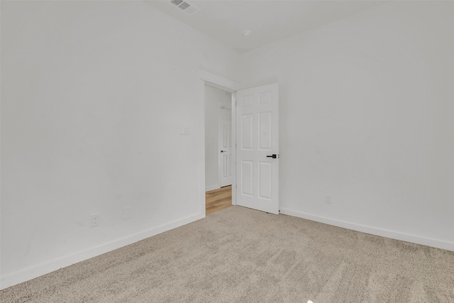 empty room featuring light colored carpet, baseboards, and visible vents