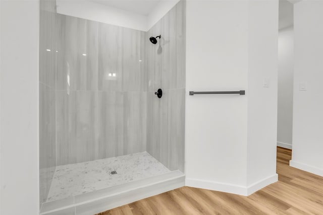 full bathroom with a shower, baseboards, and wood finished floors