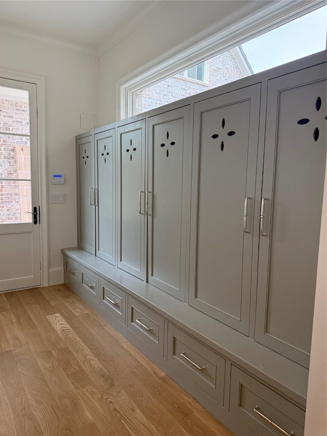 mudroom with light wood-style floors and crown molding