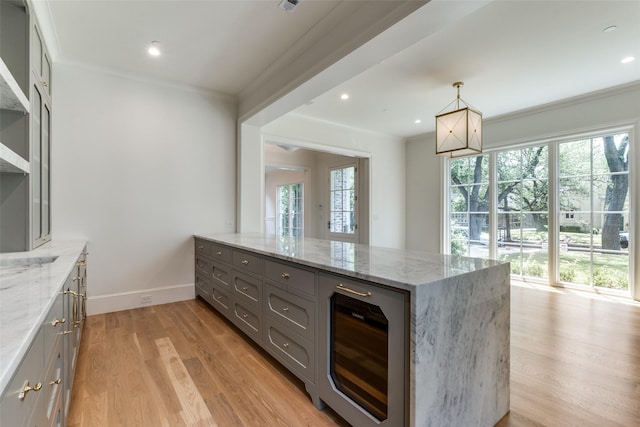 kitchen with gray cabinets, beverage cooler, healthy amount of natural light, a peninsula, and crown molding