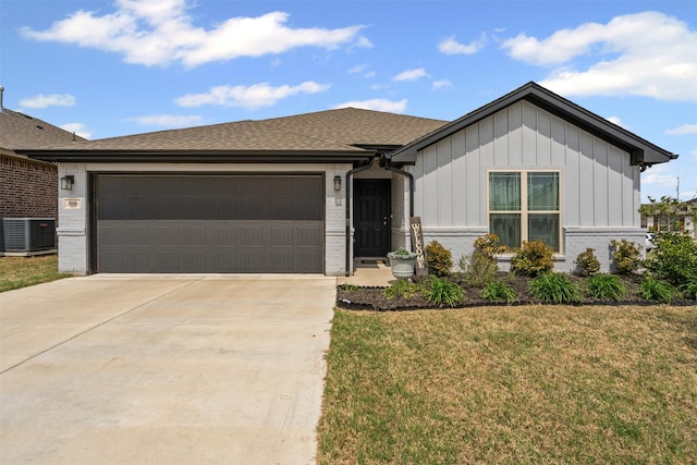 view of front of property featuring a garage, cooling unit, concrete driveway, brick siding, and a front lawn