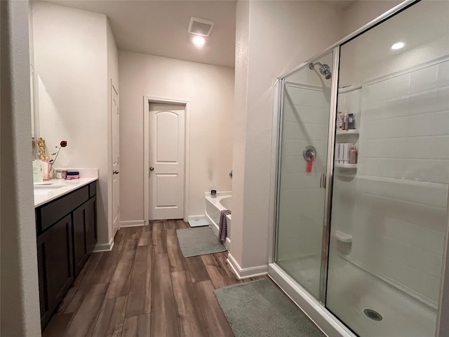 full bath with baseboards, a garden tub, a stall shower, and wood finished floors